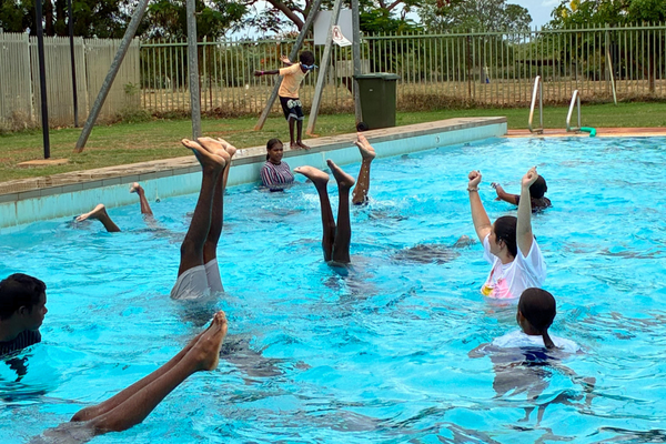 Kids practice artistic swimming - nothing but their feet is poking out above the water as they do hand stands in the pool