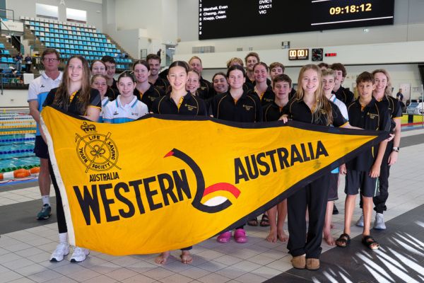 The Western Australian pool lifesaving team poses together behind a large state flag.
