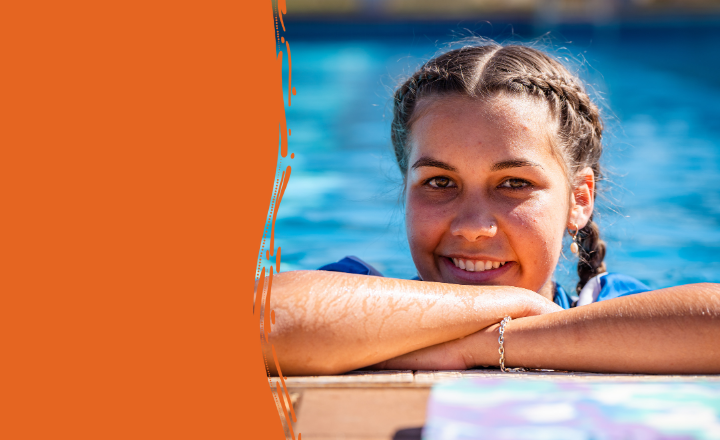 A young woman with braided hair smiles while leaning on the edge of an outdoor swimming pool. She wears a blue shirt and rests her arms on the poolside, with an orange graphic border framing the left side of the image.