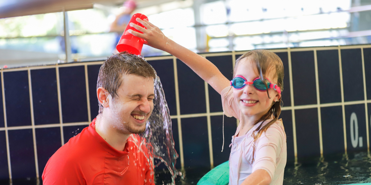 A Swim and Survive Fund recipient pours water onto her swim teachers head during a lesson
