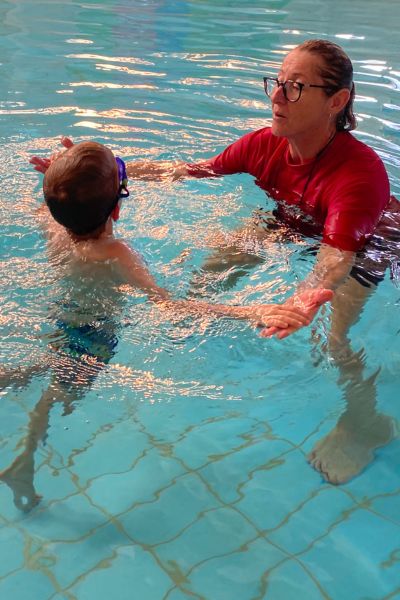 Instructor holds her student's hand while guiding them through the water