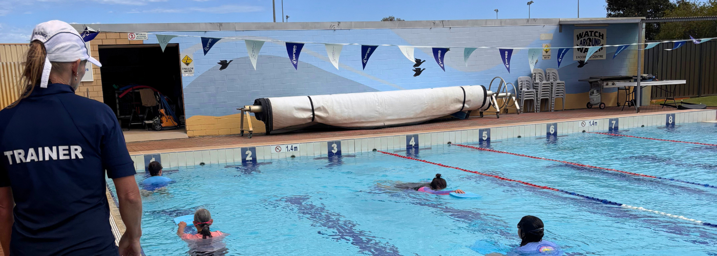 A swim teacher overlooks swimmers at the pool