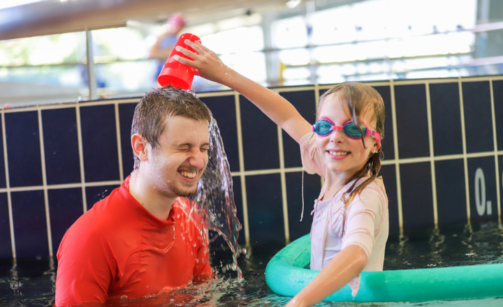 A Swim and Survive Fund recipient pours water onto her swim teachers head during a lesson