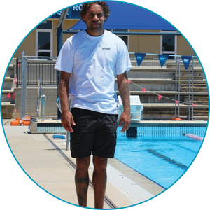 man wearing regular t-shirt and shorts standing next to a pool